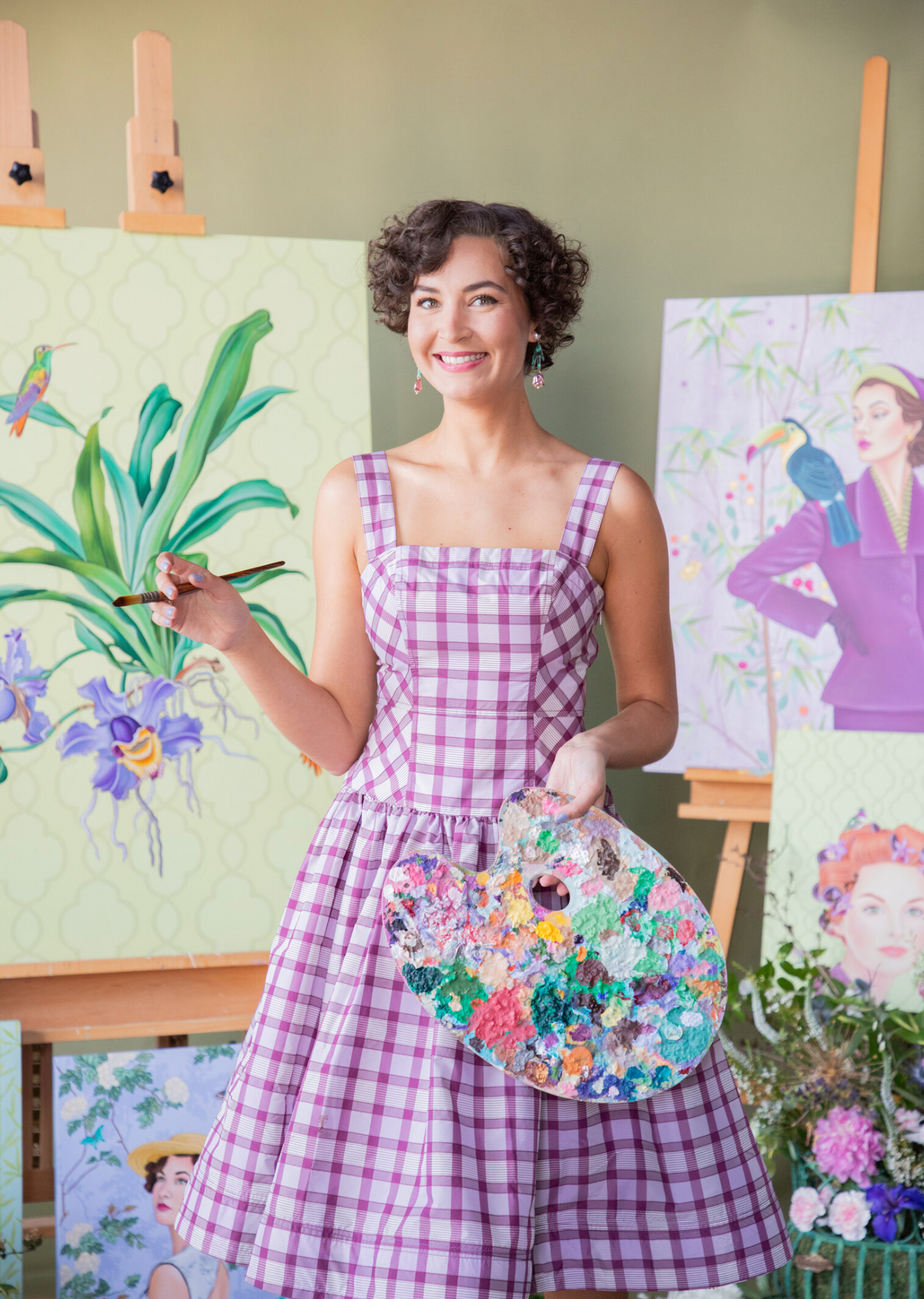 Ashton Huffstetler smiling with a paintbrush and palette in her studio