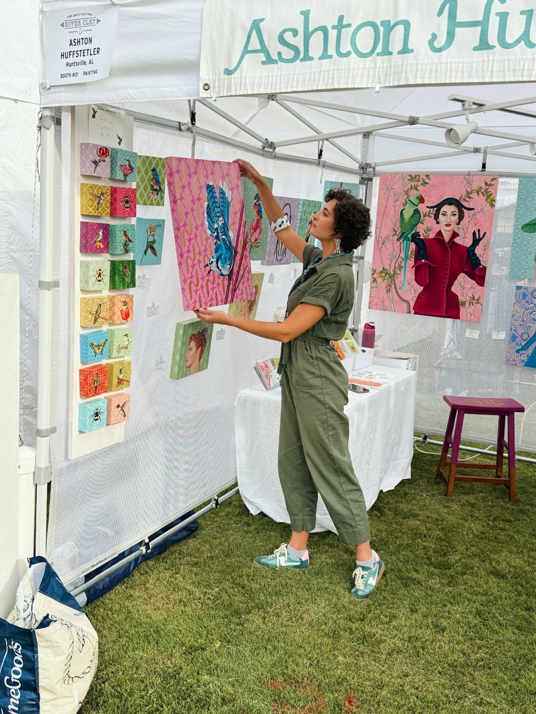 Ashton hanging a blue jay painting in her booth at River Clay Fine Arts Festival