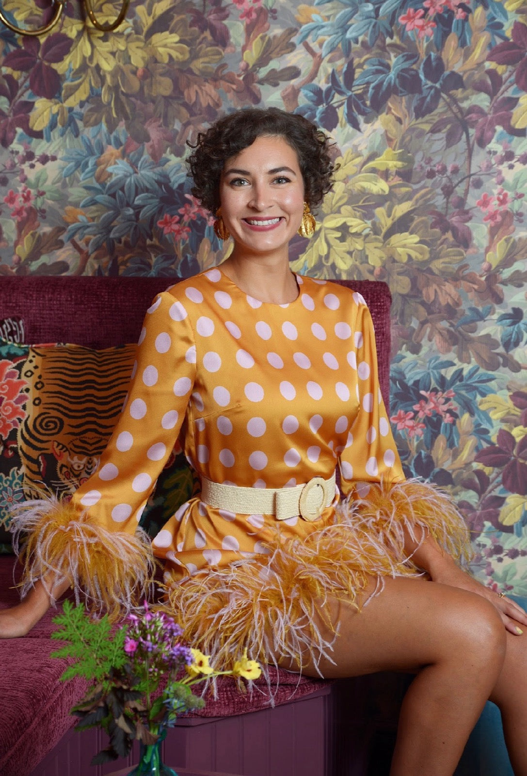 Ashton Huffstetler smiling in a gold dress in front of botanical wallpaper